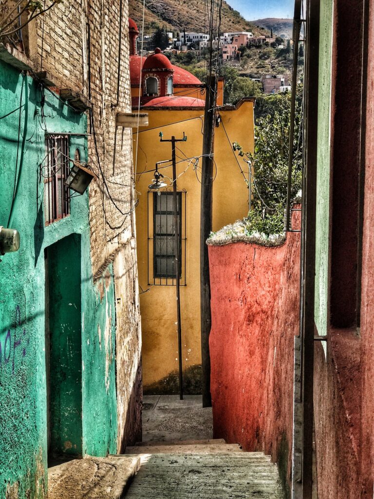 Bunte Gasse mit Treppen in der Altstadt von Guanajuato, Mexiko – typisch mexikanische Architektur und Bergkulisse im Hintergrund.